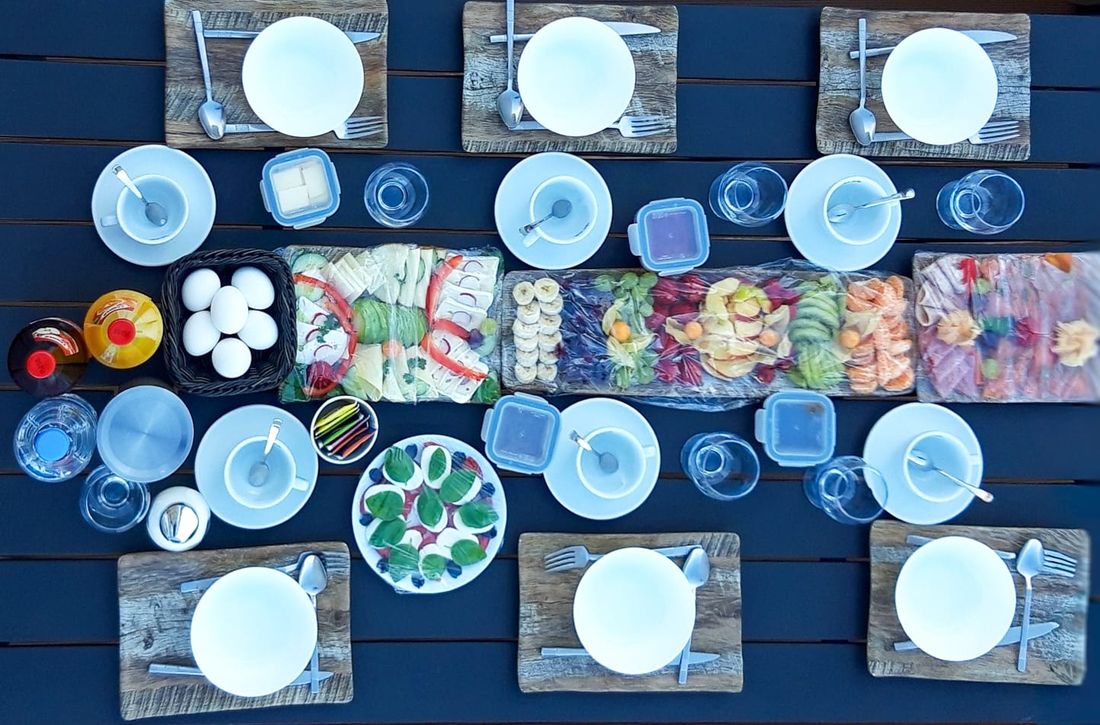 Reich gedeckter Frühstückstisch mit Obst, Aufschnitt, Eiern und Getränken an Bord
