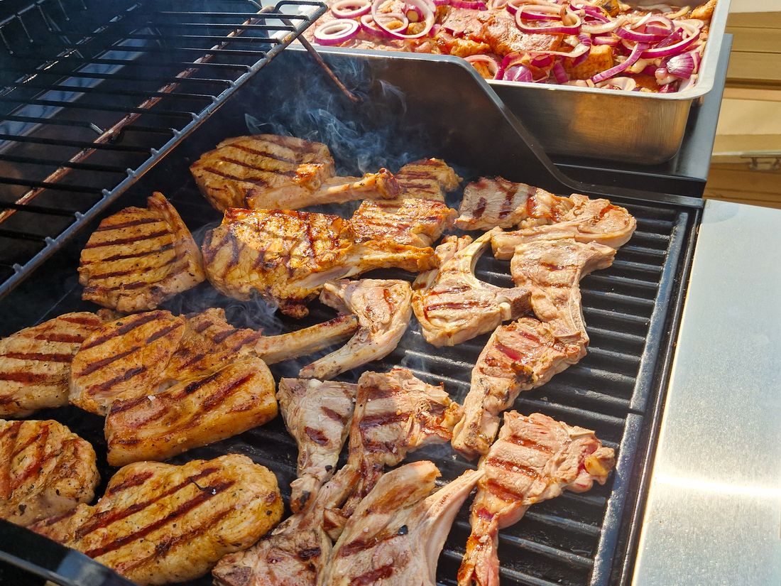Steaks und Koteletts auf dem Grill an Bord, daneben eine Schale mit Zwiebeln